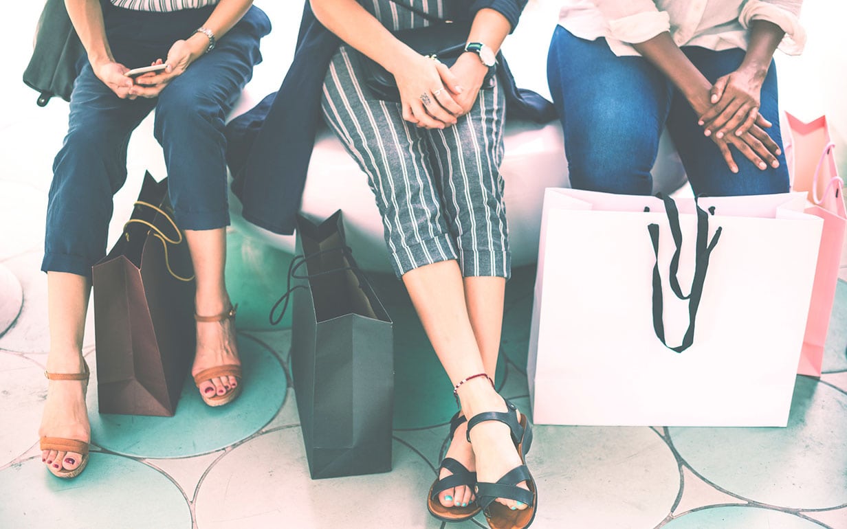 Three women sitting down with their shopping bags